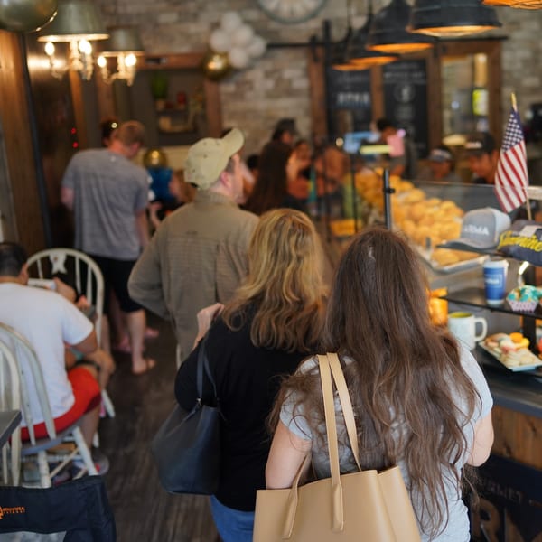 Customers waiting in line at Karma Kolache & Dessert, with pastries visible in a display case.