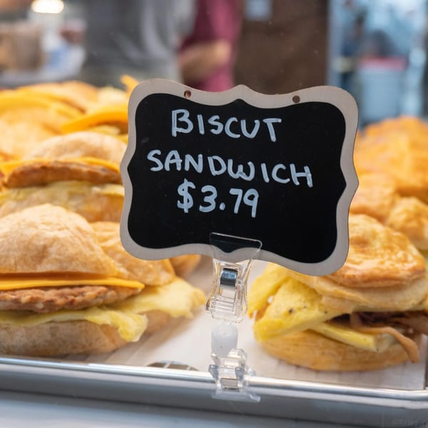 A display case filled with Karma Kolache & Dessert biscuit sandwiches, with a price tag for $3.79.